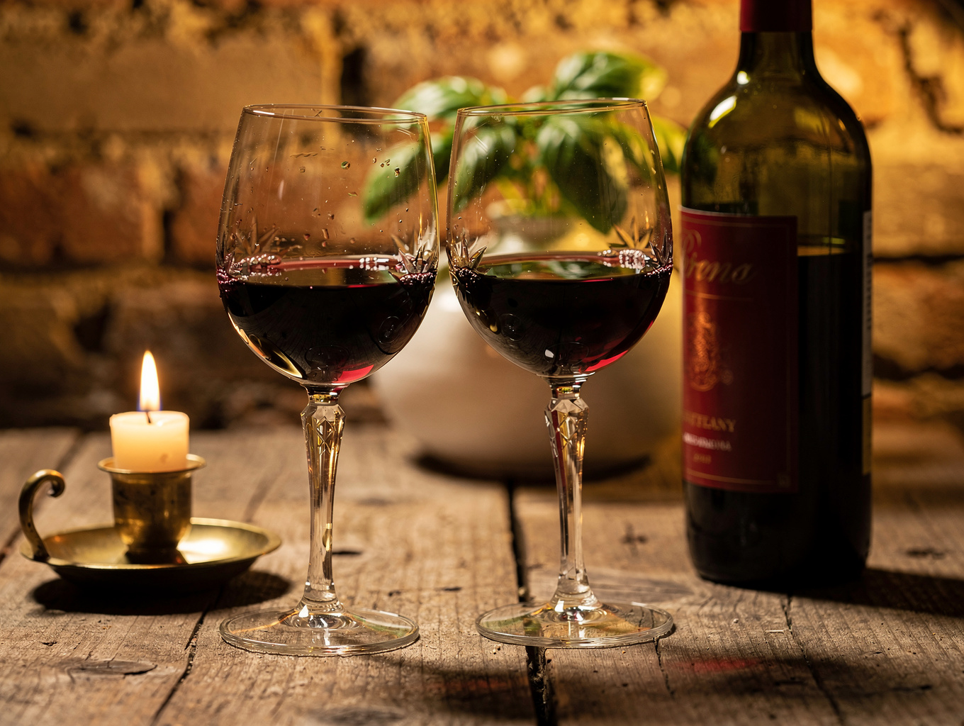 Candlelit dinner setting with wine glasses on covered veranda at twilight